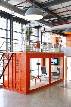 an orange container is in the middle of a large room with stairs and tables on it