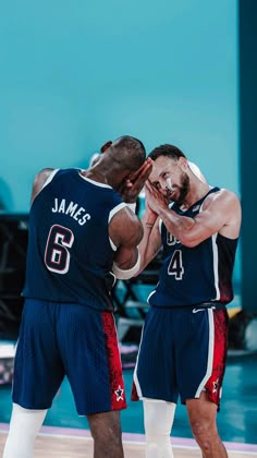 two basketball players standing next to each other with their hands in their mouths and one holding his face