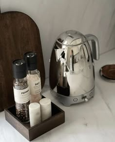 spices, salt and pepper shakers sit on a tray next to a tea kettle