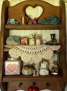 an old fashioned wooden shelf with various items on it and a heart shaped doily hanging from the top