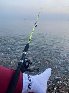 someone is holding a fishing rod on the beach