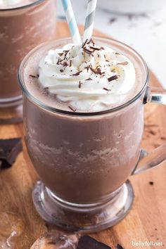 two glasses of hot chocolate with whipped cream and chocolate shavings on the rim