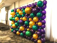 the balloon wall is decorated with many different colors and sizes, including purple, green, yellow, and orange balloons