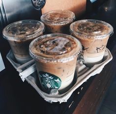 four cups of iced coffee sitting on top of a tray