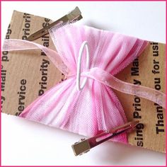 a pink ribbon wrapped in brown paper with a pair of scissors on top of it