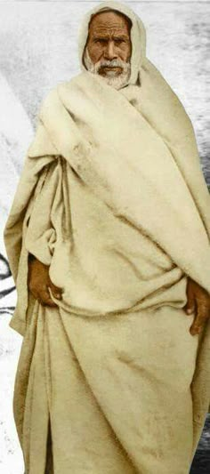 an old photo of a man with a white beard and wearing a shawl over his head