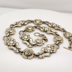 A very fine Georg Jensen necklace in sterling silver.  Model No. 10.  With alternating rose and stylized floral links, traces of its original gilding, and a toggle clasp.  Designed by Georg Jensen and bearing an old GI mark.  At approximately 14 1/2 in., the necklace is a snugly fitting, true choker.  Simply a great piece!  Date: 20th Century  Overall Condition: It is in overall good, as-pictured, used estate condition.  Condition Details: The links appear to retain some of an original gilding o Victorian Hallmarked Link Necklace, Victorian Link Necklace Hallmarked, Vintage White Gold Metal Necklace, Antique Linked Hallmarked Jewelry, Vintage Engraved Link Necklace, Vintage Engraved Link Necklaces, Silver Link Necklace With 17 Jewels, Vintage Silver Link Necklace, Vintage White Gold Link Jewelry