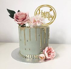 a birthday cake with flowers on top and a happy birthday sign in the middle that says mum