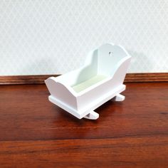 a small white baby crib sitting on top of a wooden table next to a wall