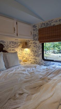 a bed with white sheets and pillows in front of a window that has an animal print on it