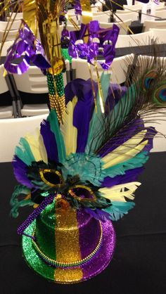 a vase filled with purple and green feathers sitting on top of a table next to chairs