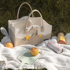 a white bag sitting on top of a blanket next to an apple