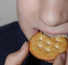 a person holding a cracker in front of their face and eating it with both hands