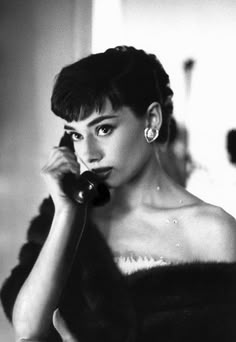 a black and white photo of a woman talking on the phone