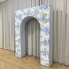 an arch made out of cardboard with blue flowers on it and curtains behind the door