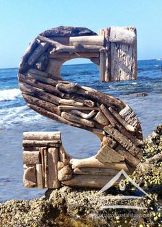 a wooden sculpture sitting on top of a beach next to the ocean