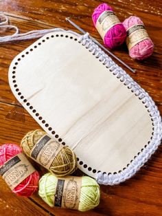 several balls of yarn sitting on top of a wooden table next to a crochet hook