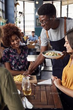 a man serving food to two women at a restaurant - stock photo - images