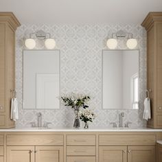 a bathroom with two sinks, mirrors and lights on the wall above them is shown