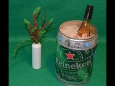 there is a beer in a can next to a small vase with flowers on it