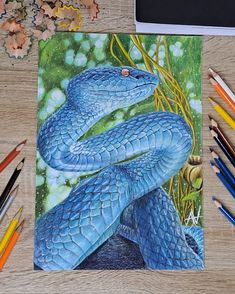 a drawing of two blue snakes on a table next to colored pencils and crayons