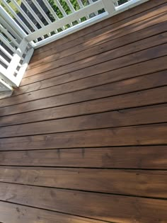 a wooden deck with white rails and railings on it's sides, looking down at the ground