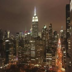 the city skyline is lit up at night, with skyscrapers in the foreground