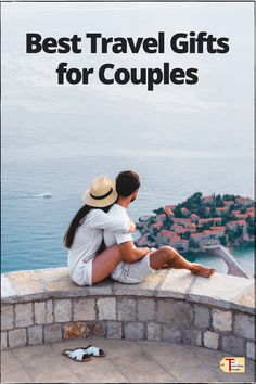 a man and woman sitting on top of a stone wall with the words best travel gifts for couples