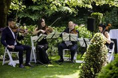 four people are playing music in the grass