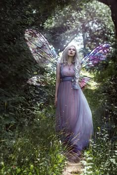 a woman dressed as a fairy standing in the woods