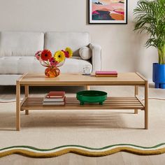 a living room with a couch, coffee table and potted plants on the floor