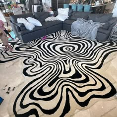 a black and white rug on the floor in a living room with couches, pillows and other furniture