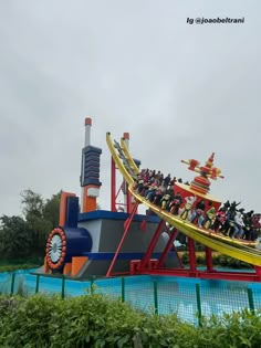 an amusement park ride with many people riding on the roller coaster and in the water