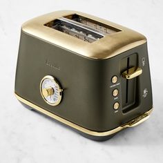 a close up of a toaster on a white counter top with gold trim and knobs