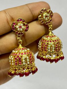 "Experience the royal heritage of Hyderabadi jewelry with this exquisite Jhumka set, handcrafted with love and precision. This stunning piece features: - Intricately designed brass Jhumkas adorned with Polki stones and Quartz stones - Delicate filigree work and textured details, reminiscent of traditional Hyderabadi craftsmanship - Dangling tassels that add movement and flair - Comfortable ear wires and a secure clasp for all-day wear Inspired by the rich cultural legacy of Hyderabad, this Jhumk Temple Jewelry Style Ruby Chandbalis With Latkans, Festive Ruby Jhumkas In Temple Jewelry Style, Festive Ruby Jhumkas With Intricate Design, Ruby Temple Jewelry Jhumkas For Festive Occasions, Festive Ruby Temple Jewelry Jhumkas, Traditional Jhumkas With Intricate Design For Eid, Traditional Intricate Jhumkas For Eid, Traditional Red Gold-plated Bridal Earrings, Ruby Temple Jewelry Danglers For Celebration