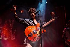 a man holding an orange guitar on stage