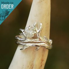 We are excited to introduce THE BUNDOLYN! We worked with an amazing artisan out of California to make this handmade beauty. This ring features a stunning raw, natural diamond surrounded by a beautiful and unique Sterling Silver bud branch. 2 rings included in this set. The band is hand-formed from a sheet of sterling silver and wire to create a stunning authentic design. ABOUT THIS RING Gemstones: Natural Raw Diamond Metal: Sterling Silver Color/Finish: Silver, Polished QUESTIONS ABOUT SIZING Go Antler Engagement Ring, Antler Rings, Antler Wedding Band, Deer Antler Ring, Hunter Wedding, Antler Ring, Engagement Ring For Her, Engagement Sets, Two Rings