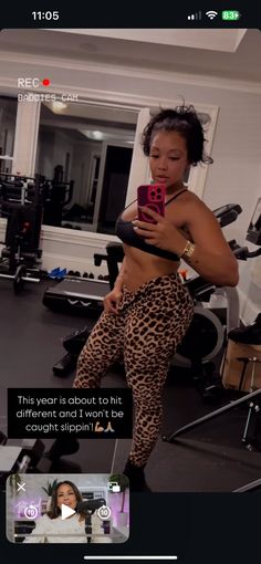 a woman in leopard print pants is looking at her cell phone while standing on a stationary exercise machine