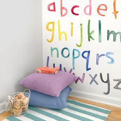 a child's room with colorful pillows and alphabets painted on the wall behind them