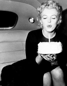 a woman blowing out the candles on her birthday cake while sitting in a car,