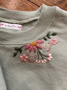 an embroidered t - shirt with pink flowers on it