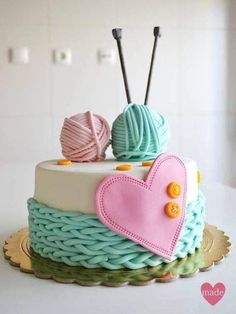 a cake decorated with yarn and knitting needles