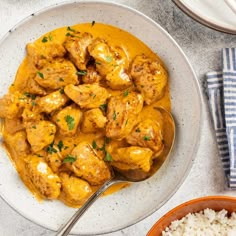 a white plate topped with chicken and gravy next to rice