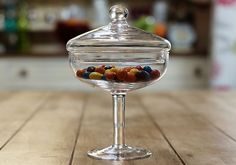 a glass bowl filled with candy sitting on top of a wooden table