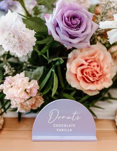 a bouquet of flowers sitting on top of a table next to a sign that says donut chocolate vanilla