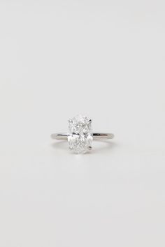 an oval cut diamond engagement ring on a white background