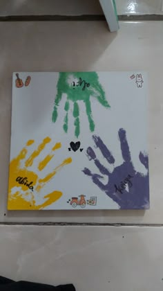 handprints on a white board with different colors and shapes in the middle, sitting on a tile floor