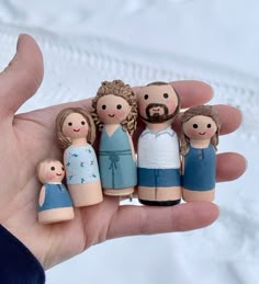 a hand holding a small group of wooden dolls