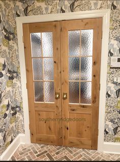 two wooden doors in front of a floral wallpaper