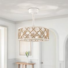 a white chandelier hanging from the ceiling in a living room with a table and chair